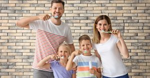 A family is practicing at-home general dentistry by brushing their teeth.
