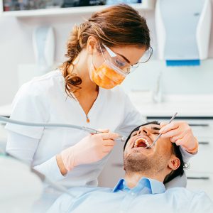 Male patient getting his teeth examined by a female hygienist