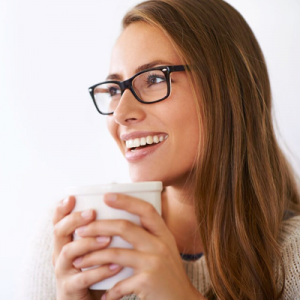 Young woman smiling and holding a drink followin gher restorative dentistry procedure.