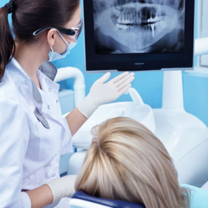 Dental professional discussing impacted wisdom teeth with patient, showing X-ray on monitor, emphasizing comprehensive evaluation and treatment options at Davie Advanced Dentistry.