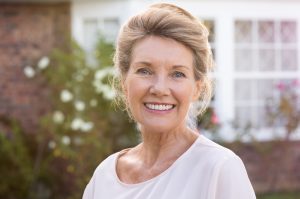 A woman is smiling and showing her beautiful dental implants.